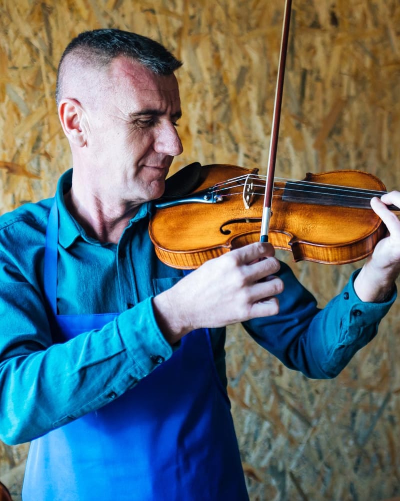 Elvedin Hodžić in his workshop, trying out the sound of a newly finished violin