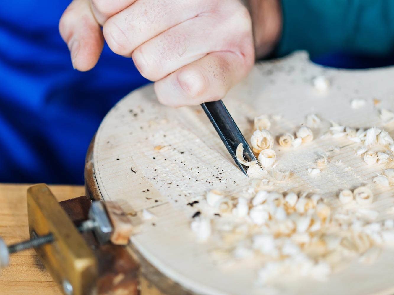 Shaping the arching of a violin top plate by hand with a gouge, surrounded by shavings