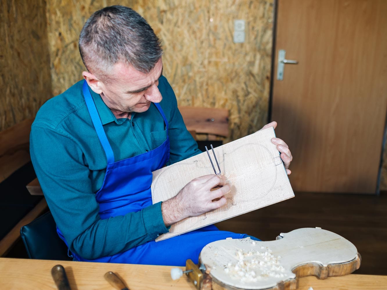 The maker checks the resonance of a top-plate board with a tuning fork