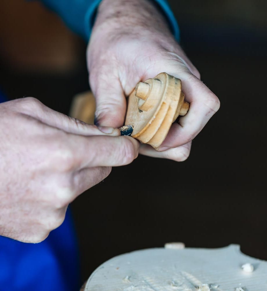The maker's hands carving a maple violin scroll by hand
